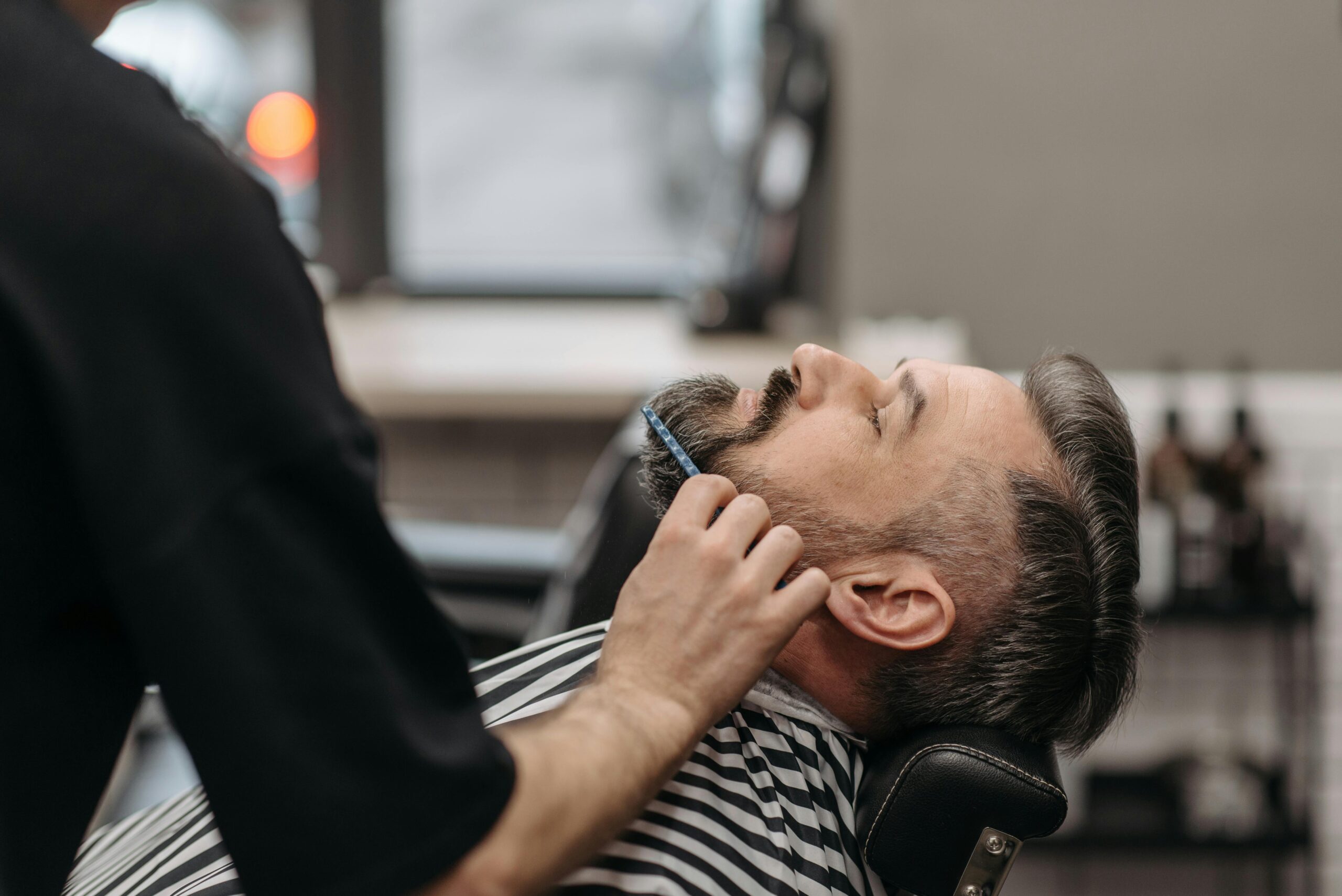 Close-up of a barber styling a man's beard in a modern salon, showcasing grooming techniques.